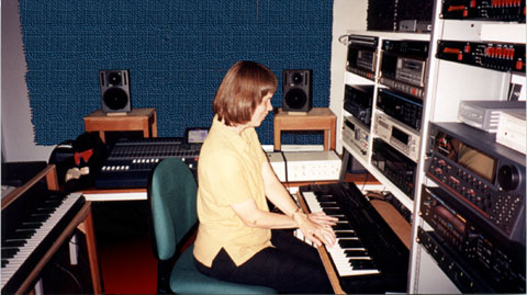 Here is a picture of Veronica working
in her studio. She is playing a synthesizer keyboard. She is surrounded by
other keyboards, computers, synthesizers, rack mounted recording equipment,
teddy bear, speakers, mixing console, and other essential gear. Caption:
