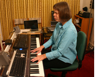 Picture: Veronica singing and playing a synthesizer keyboard. She is surrounded by studio equipment.