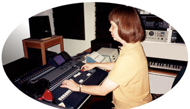 Here is a picture of Veronica
at the mixing console. It shows her listening intently to the speakers and adjusting
faders. It also shows the audible VU meters, a teddy bear, and some of her recording 
equipment.